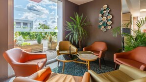 A modern interior with a glass door leading to a balcony, a round table, and two leather chairs.