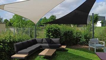 An outdoor seating area with a sectional sofa, two wooden tables, and a chair.