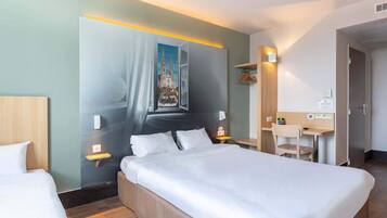 A hotel room with a large bed, bedside tables, a desk, and a chair.