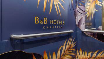A blue wall with gold leaf patterns and the text "B&B Hotels Chartres".