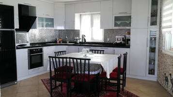 Une cuisine moderne avec des meubles blancs, une hotte noire et un coin repas comprenant une table et des chaises.