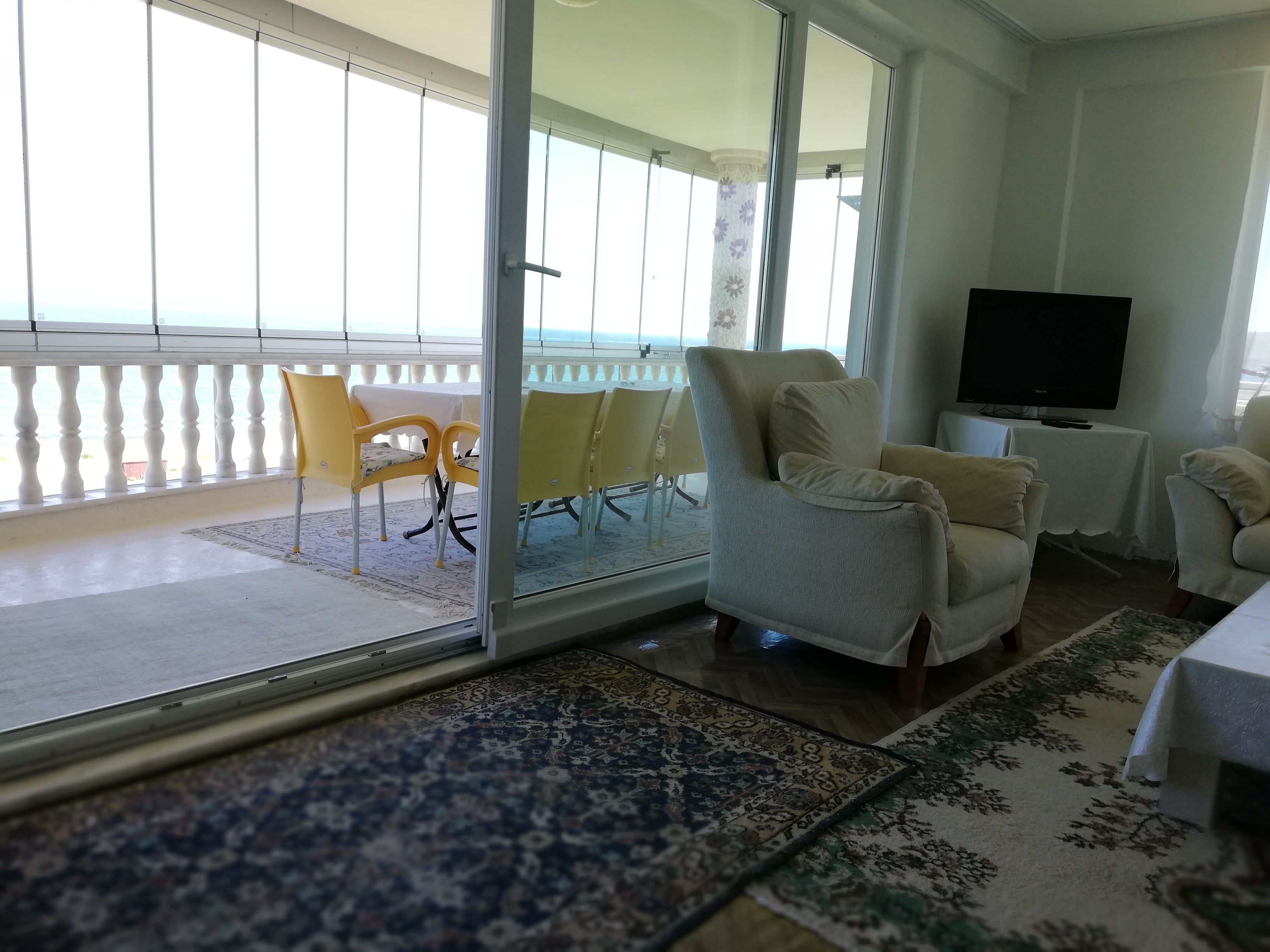 Una habitación con balcón, televisión y zona de estar con sillas y una mesa.