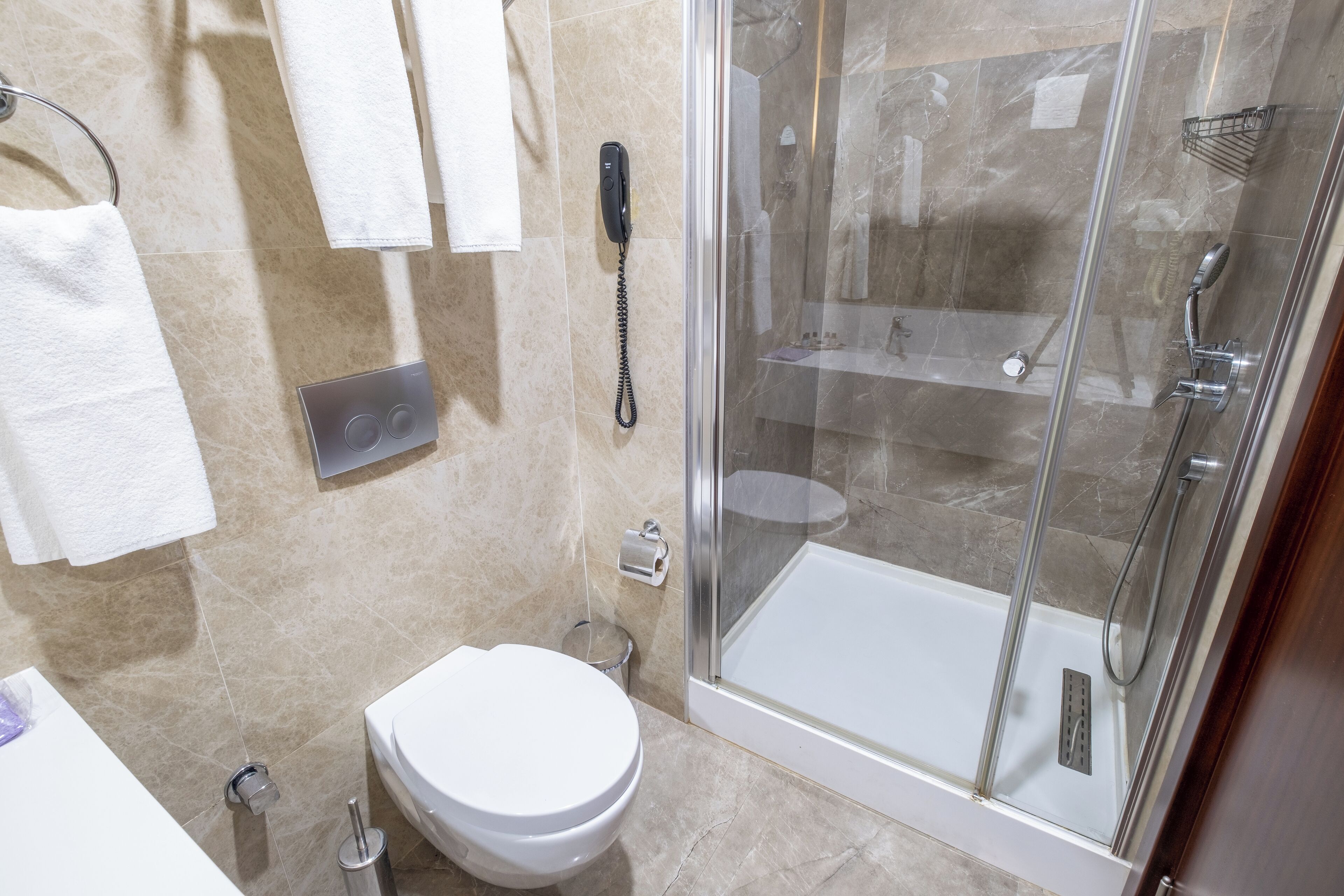 A modern bathroom with a glass-enclosed shower, a toilet, and a sink.