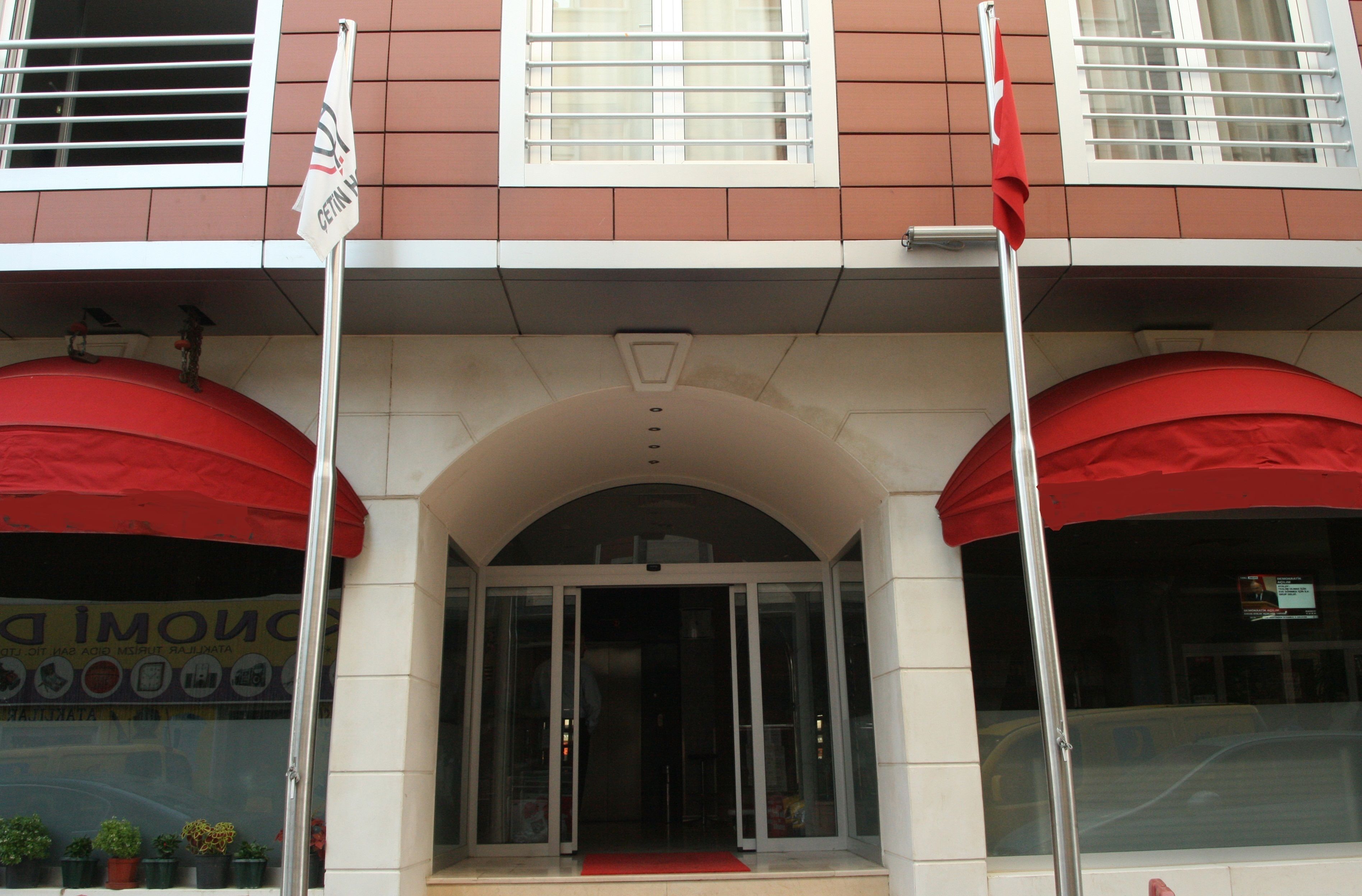 A building entrance with a red awning, a glass door, and a flag.