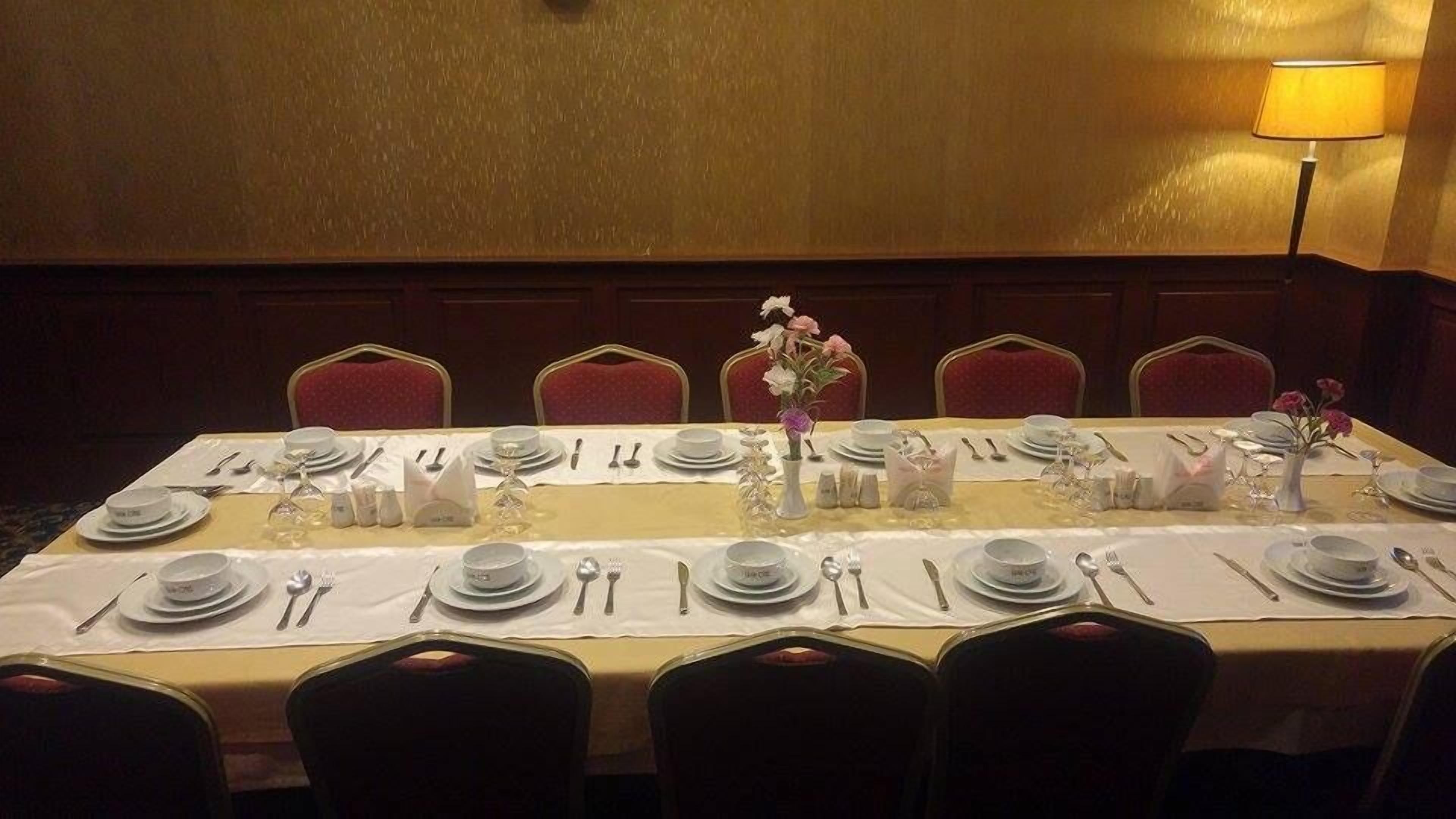 A dining table set for a formal meal with white tablecloths, silverware, and floral centerpieces.