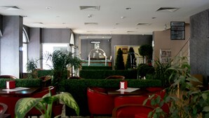 A restaurant with a reception area, red chairs, and potted plants. - Cetin Otel (Kesan)