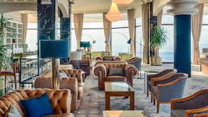 A spacious lobby with leather sofas, a coffee table, and a view of the sea. - Mercure San Sebastian Monte Igueldo (San Sebastián)