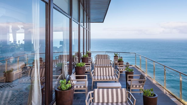 A balcony with seating and potted plants, overlooking a body of water. - Mercure San Sebastian Monte Igueldo (San Sebastián)