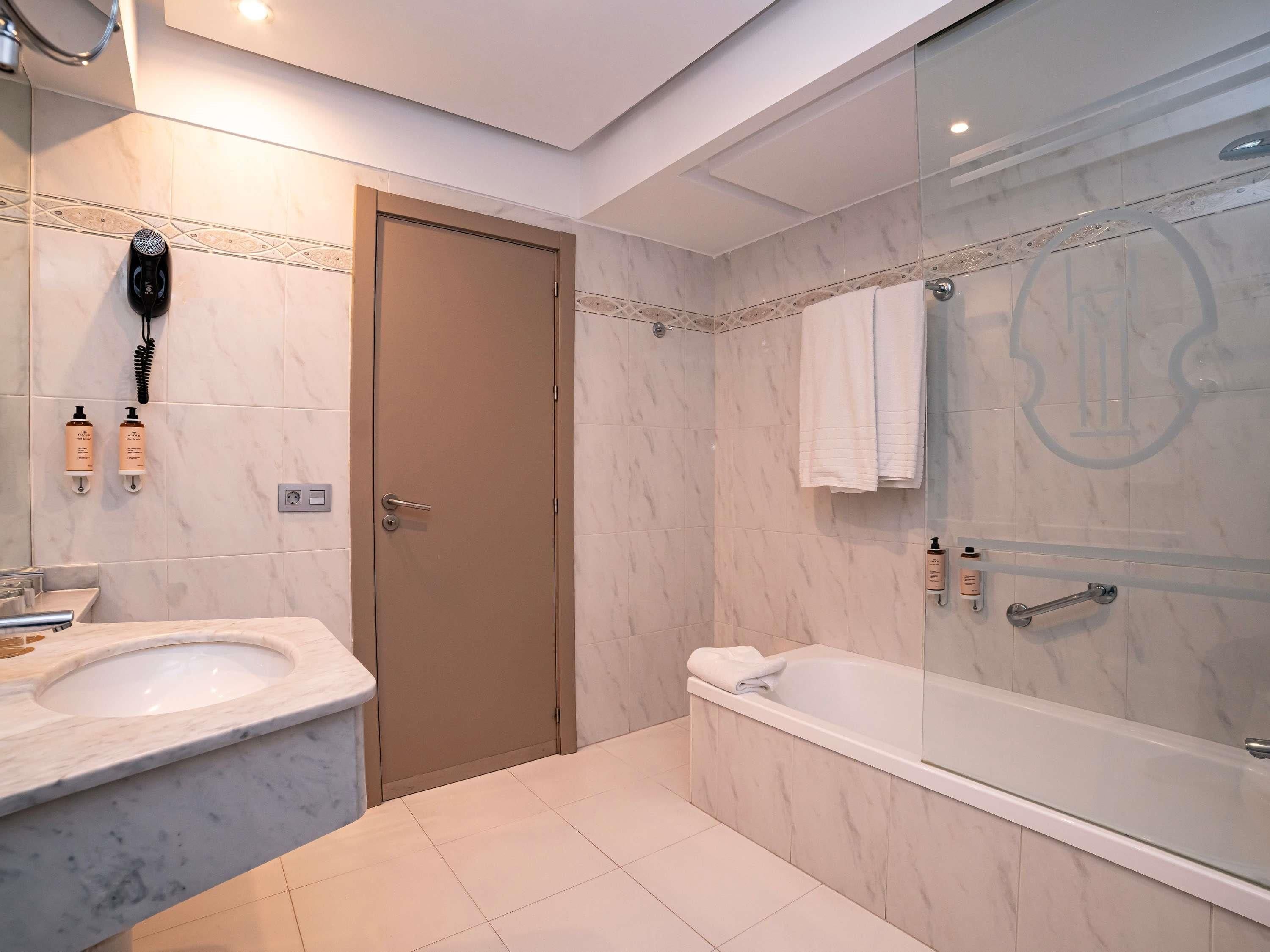 A modern bathroom with two sinks, a bathtub, and a glass shower enclosure.