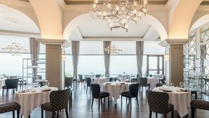 A restaurant with round tables, patterned chairs, and a chandelier. - Mercure San Sebastian Monte Igueldo (San Sebastián)