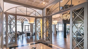 A spacious lobby with a high ceiling, modern chandeliers, and a view of a dining area. - Mercure San Sebastian Monte Igueldo (San Sebastián)