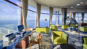 A modern hotel room with a large window offering a sea view, a desk with a computer, and comfortable seating areas. - Mercure San Sebastian Monte Igueldo (San Sebastián)