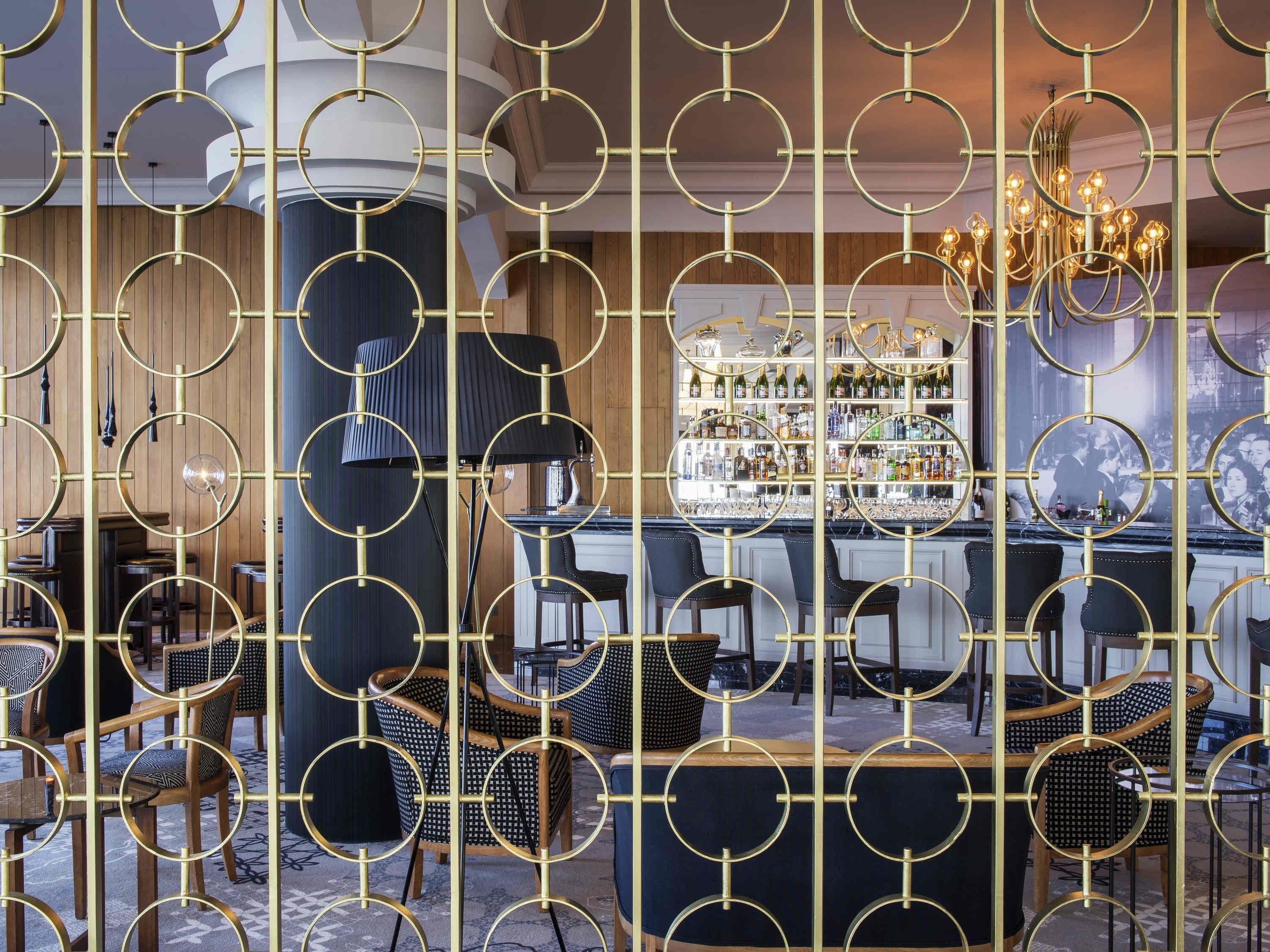 A bar area with a circular gold frame, a chandelier, and a wine rack.