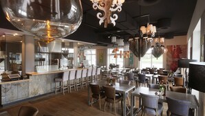 A modern restaurant with a bar area, wooden tables and chairs, and pendant lighting. - Easy Living Hotel (List)