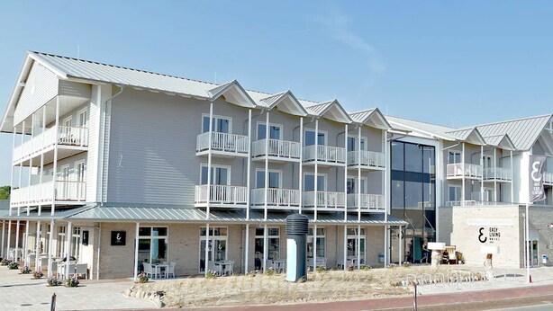 A multi-story hotel with balconies, outdoor seating, and a sign for 'Easy Living'. - Easy Living Hotel (List)