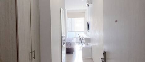 A narrow hallway with a door on the left and a window on the right.
