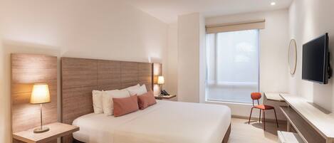 A modern hotel room with a large bed, bedside lamps, a desk with a chair, a television, and a window with a view.