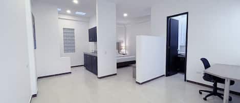 Un dormitorio moderno y bien iluminado con cama, mesita de noche y una pequeña zona de escritorio.