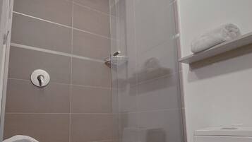 Un baño con cabina de ducha de vidrio, inodoro y barra para toallas.