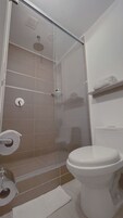 Un baño con cabina de ducha de vidrio, inodoro y barra para toallas.
