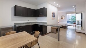 A modern kitchen with dark cabinets, a granite countertop, and a dining area with a wooden table and wicker chairs. - MS Pacífico Chipichape Plus (Cali)