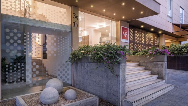 A modern building with a glass facade, a staircase, and a sign indicating the address. - MS Pacífico Chipichape Plus (Cali)