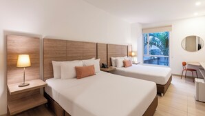 A hotel room with two beds, a desk, a chair, a lamp, and a window with a view of palm trees. - MS Pacífico Chipichape Plus (Cali)