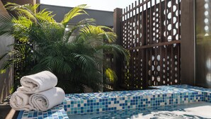 A spa area with a tiled hot tub, a stack of towels, and a palm tree. - MS Pacífico Chipichape Plus (Cali)