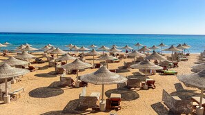 Na praia, espreguiçadeiras, guarda-sóis, toalhas de praia