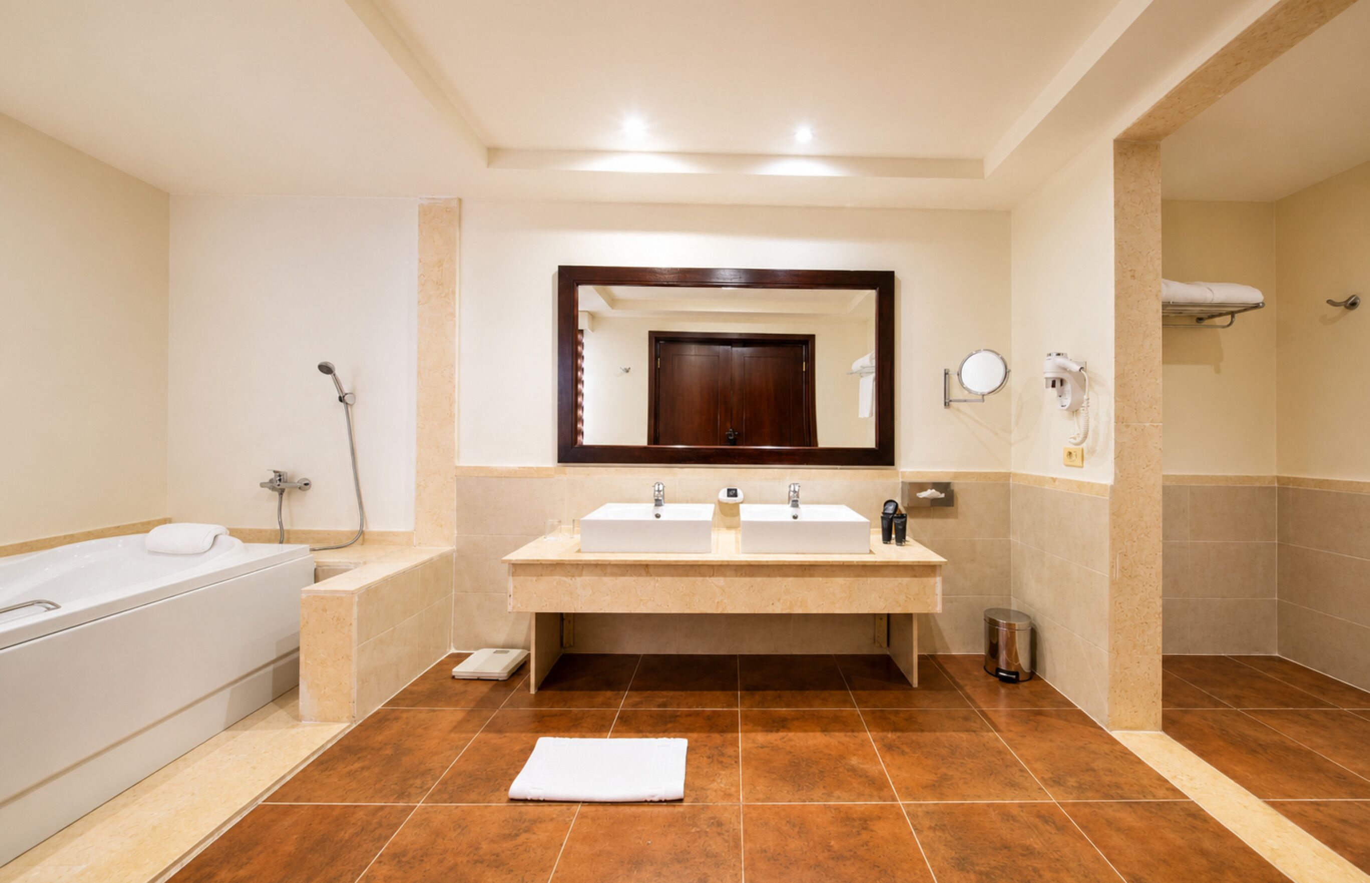Een moderne badkamer met een bad, twee wastafels, een spiegel en een douche.