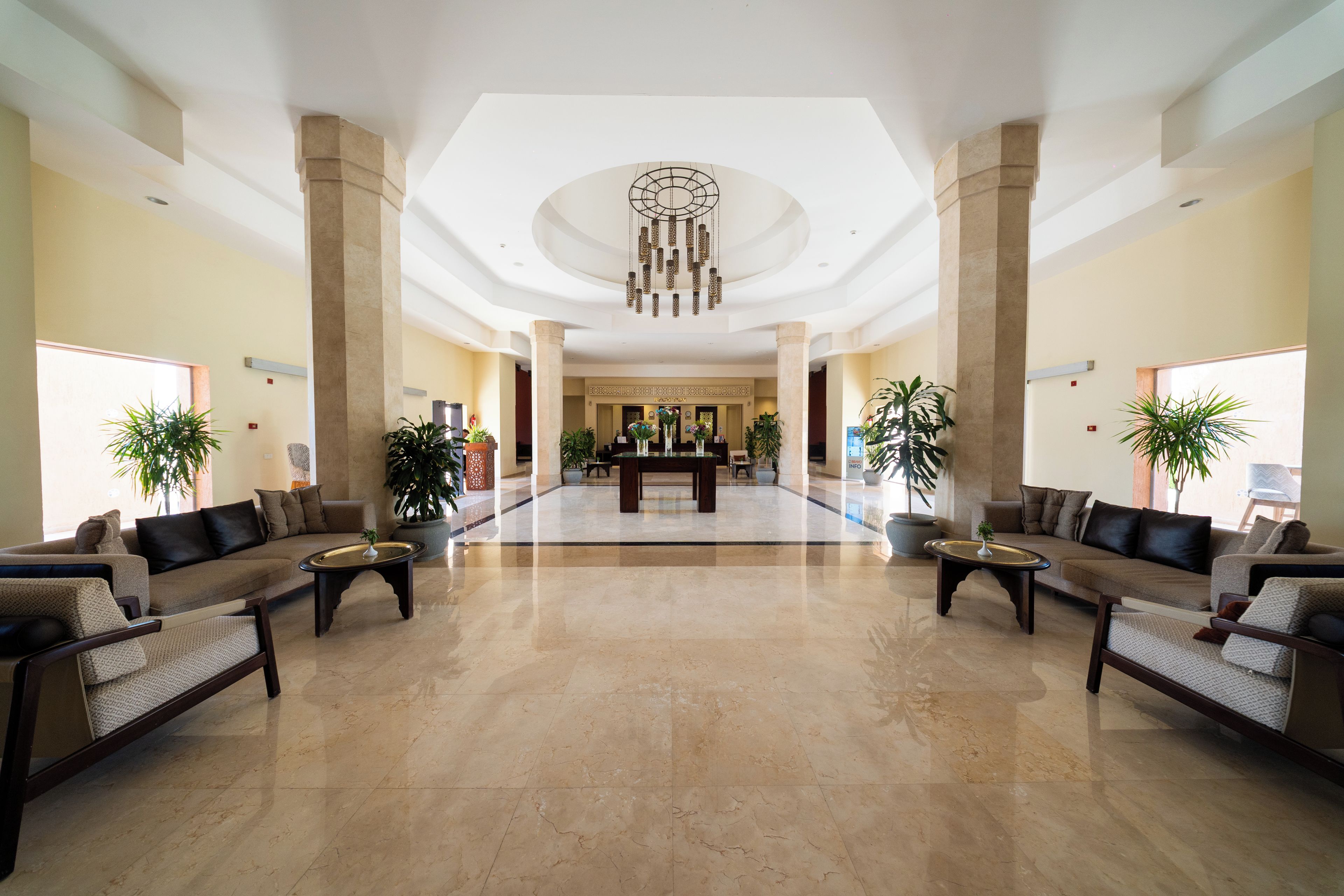 A spacious lobby with a reception desk, seating area, and decorative plants.