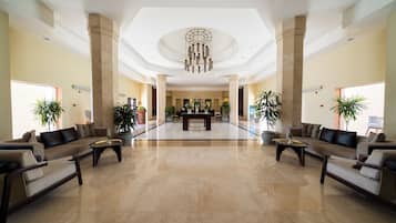 A spacious lobby with a reception desk, seating area, and decorative plants.