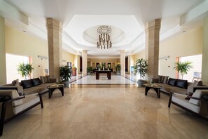 A spacious lobby with a reception desk, seating area, and decorative plants. - Gemma Resort (Marsa Alam)