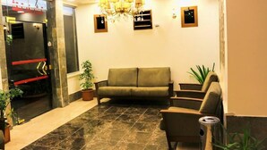 A lobby with a sofa, chairs, a chandelier, and a reception desk. - Al-Riyati For Hotel Apartments (Aqaba)