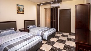 A hotel room with two beds, a checkered floor, a painting on the wall, and an air conditioning unit. - Al-Riyati For Hotel Apartments (Aqaba)