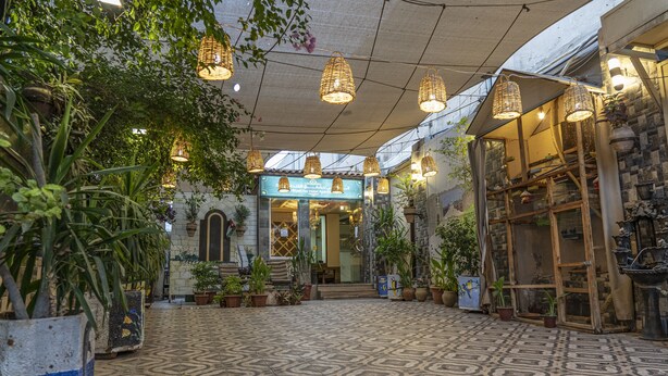 A spacious indoor area with patterned flooring, hanging wicker lamps, and potted plants. - Al-Riyati For Hotel Apartments (Aqaba)