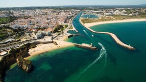 An aerial view of a coastal city with a prominent beach, a marina, and dense urban development. - A04 - Large Modern 1 bed Apartment with pool by DreamAlgarve (Lagos)