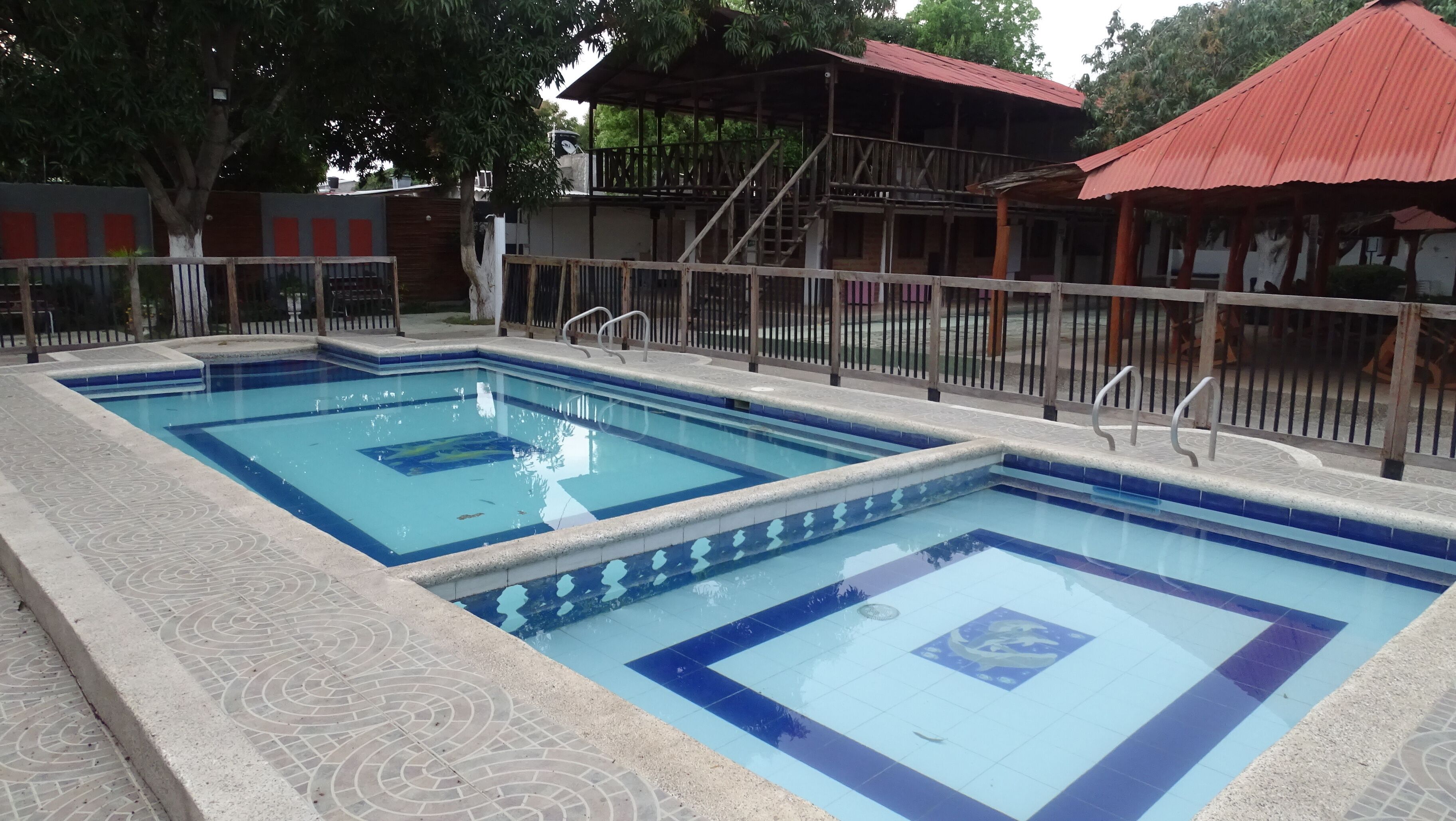 Una piscina rectangular con azulejos azules y un borde estampado.