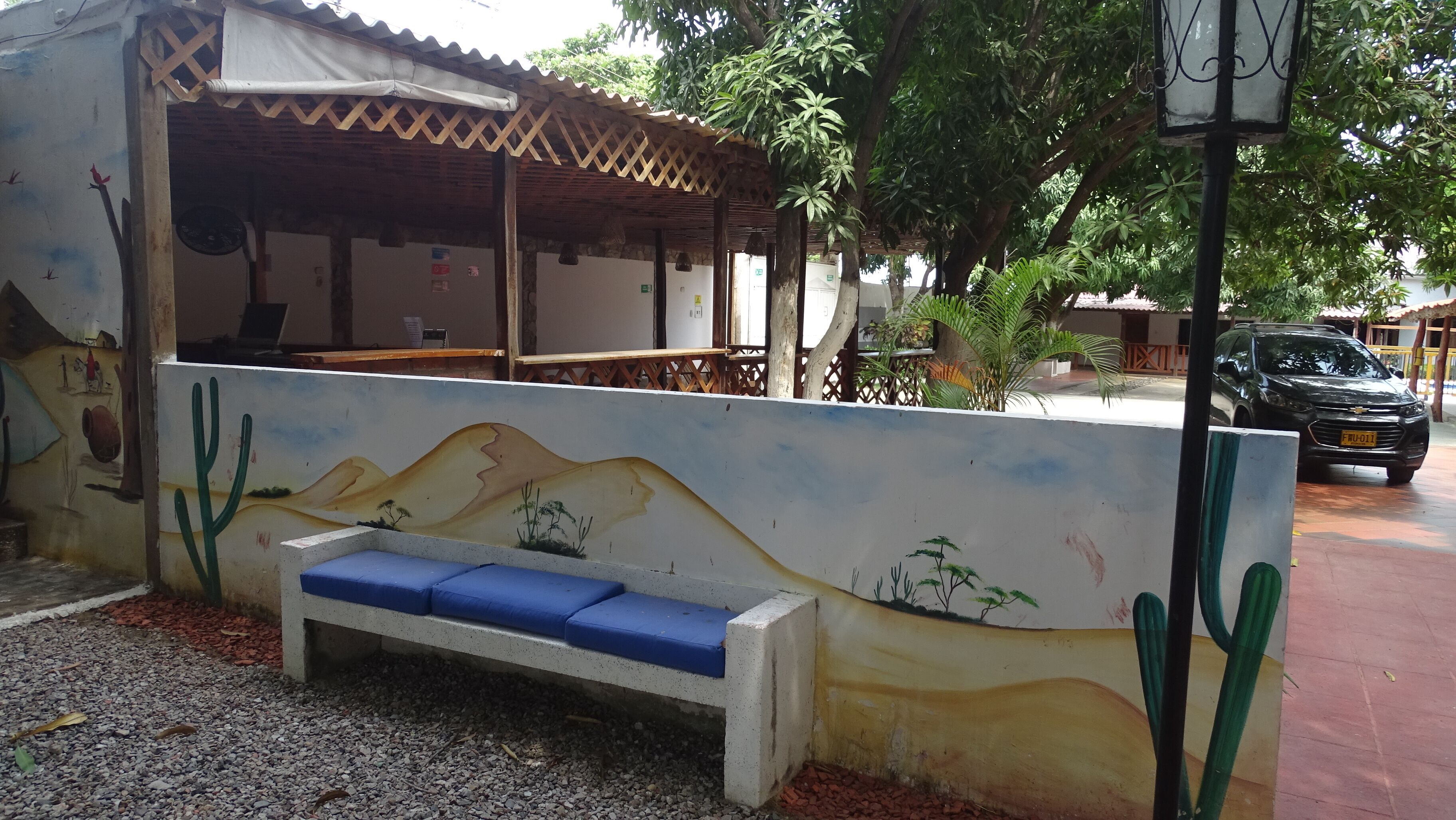 A building with a mural, a bench, and a car parked outside.