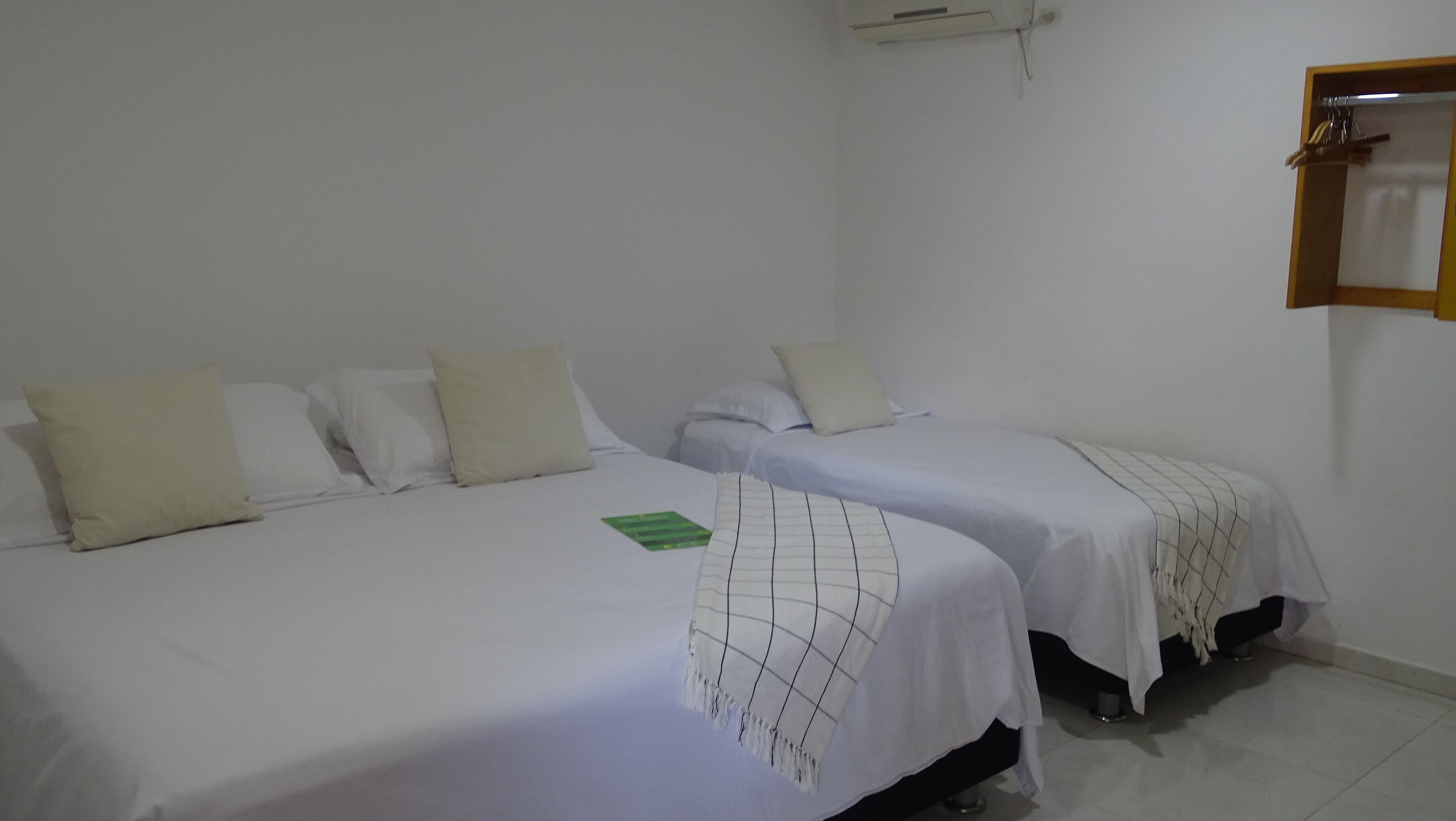 Une chambre d’hôtel avec deux lits simples, une petite table et un climatiseur fixé au mur.