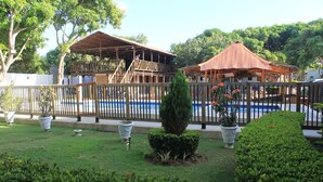 Ein Poolbereich mit Holzgazebos und einer eingezäunten Terrasse.