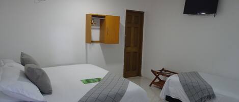 Un dormitorio con dos camas, un armario de madera, un televisor y una puerta.