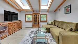 Un vaste espace de vie comprenant un canapé, une table basse en verre, des meubles en bois et un téléviseur.