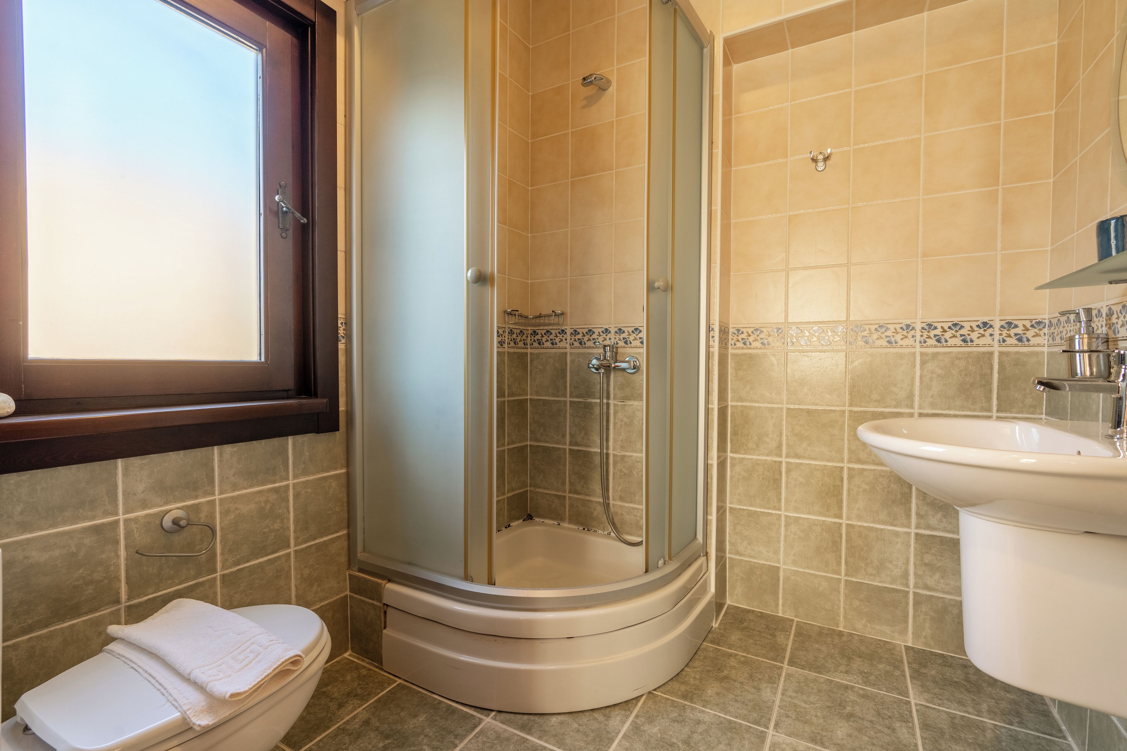 A bathroom with a shower enclosure, toilet, and sink.