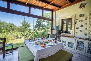 A dining area with a table set for a meal, a bench, and a view of the outdoors. - Bagbadem Tatil Ciftliği (Bozcaada)