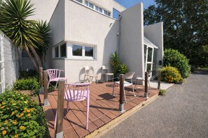 Un edificio moderno con un patio que tiene asientos exteriores e plantas en macetas.