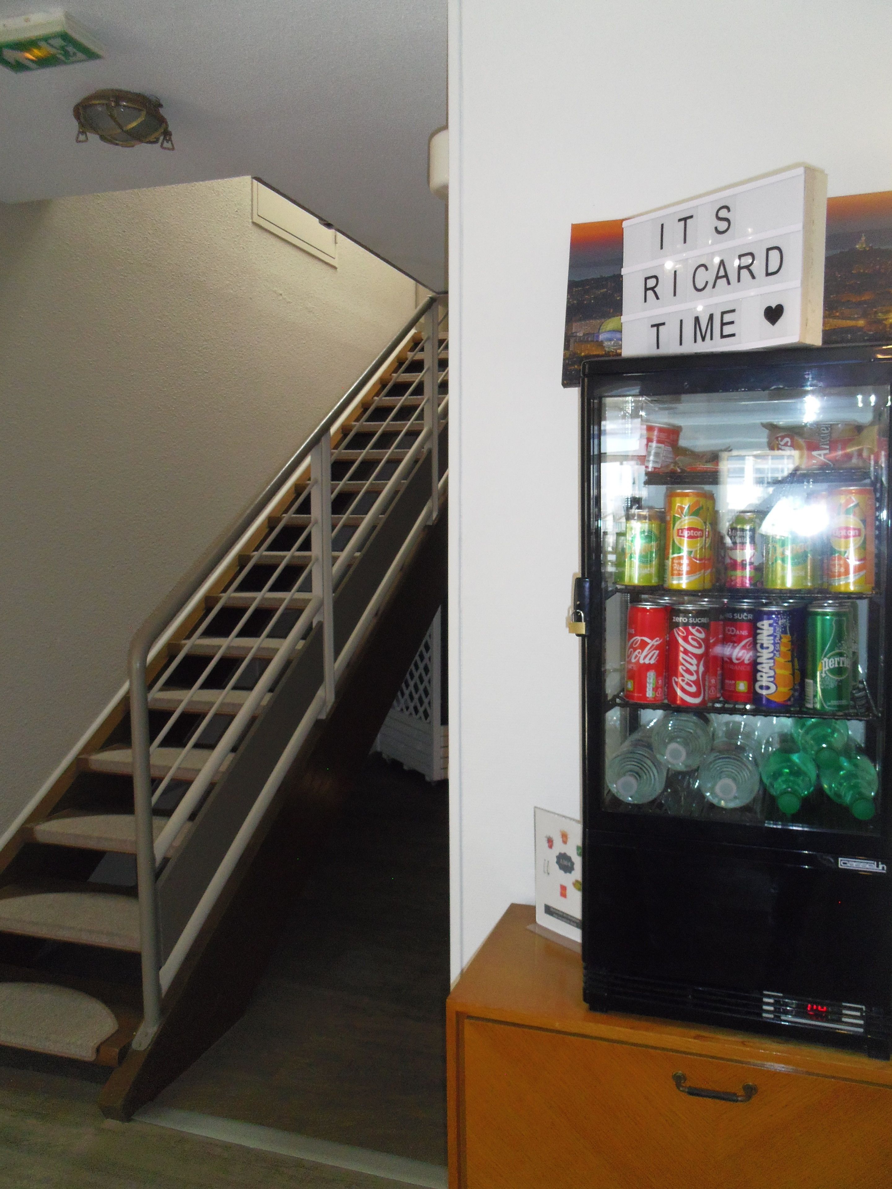 Ein Kühlschrank voller Getränke und ein Schild darüber mit der Aufschrift 'IT'S RICARD TIME'.