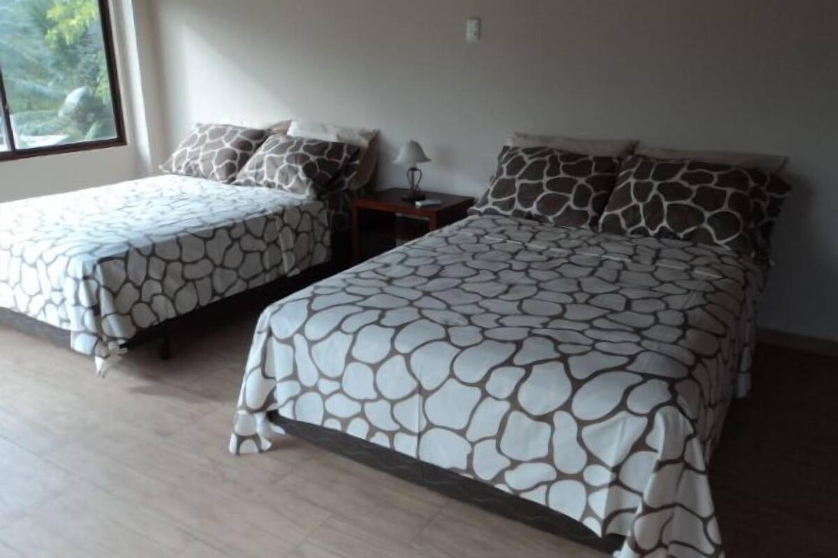 Ein Schlafzimmer mit zwei Betten, jeweils mit einem gemusterten Bettüberwurf, einem Nachttisch und einer Lampe.