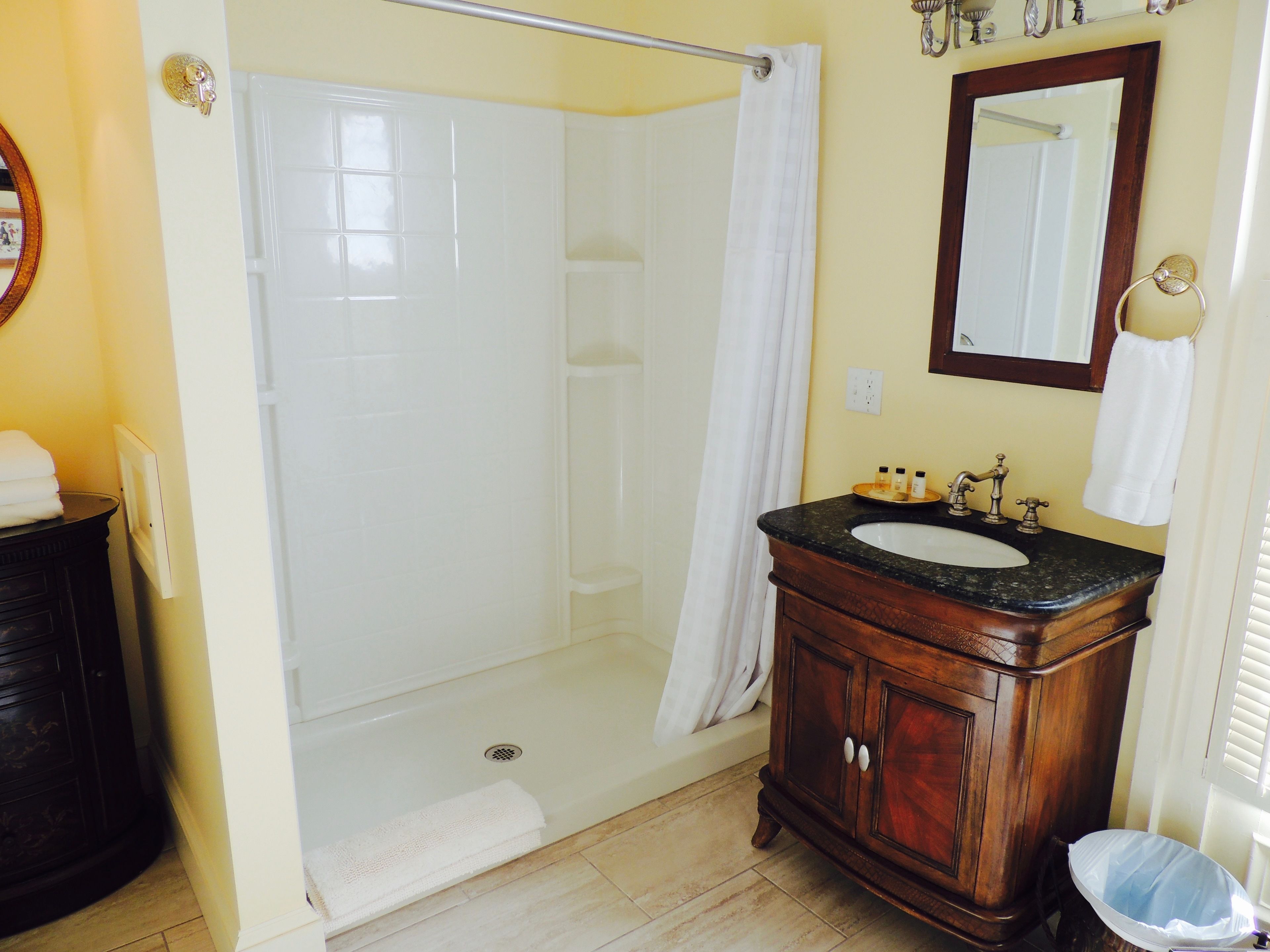 A bathroom with a shower, a sink with toiletries, and a mirror.