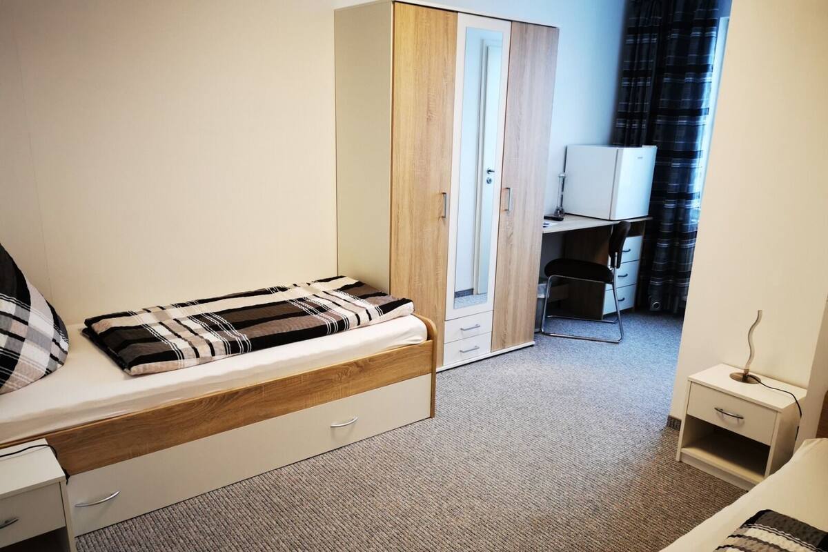 Un dormitorio con cama, armario, escritorio y silla.